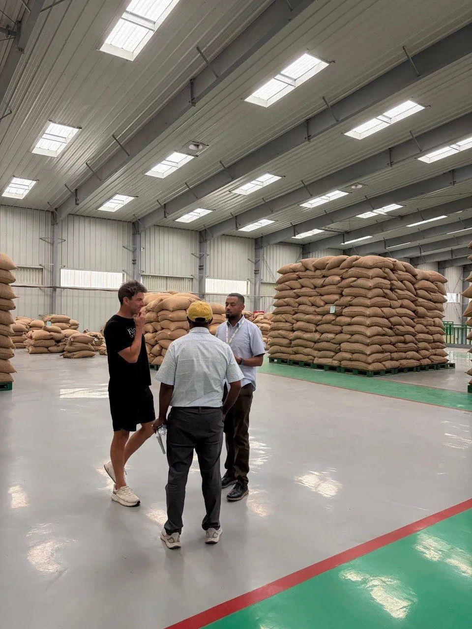 Daniel Crenshaw at a green coffee export warehouse discussing a Fourth Man Roasters shipment